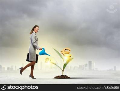 Money making concept. Image of businesswoman watering money tree with pot