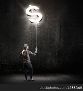 Money making. Young woman in casual holding balloon shaped like dollar