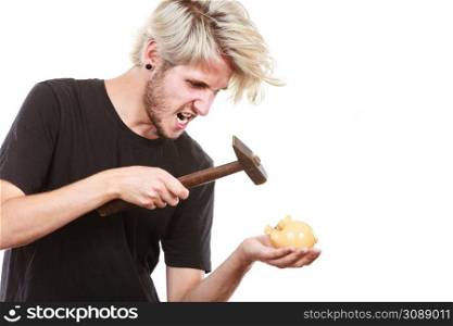 Money, savings, finances concept. Angry sreaming young blonde man wearing black t shirt trying to break piggy bank with hammer, studio shot isolated. Sreaming man trying break piggy bank with hammer