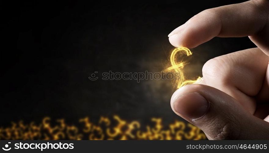 Money symbol between fingers. Tiny pound currency sign holden between fingers