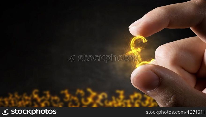 Money symbol between fingers. Tiny pound currency sign holden between fingers