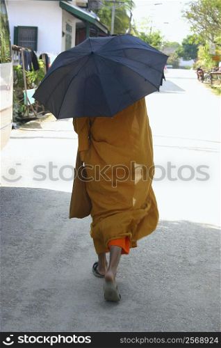 Monk holding an umbrella and walking on the road, Vientiane, Laos