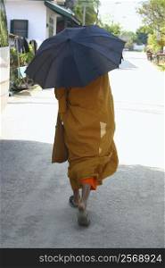 Monk holding an umbrella and walking on the road, Vientiane, Laos