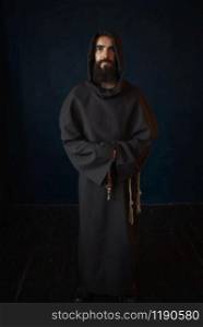 Monk in black robe with hood, religion. Mysterious friar in dark cape