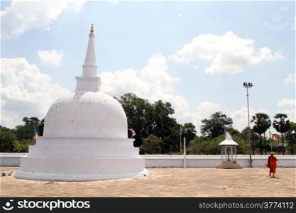 Monk walk near white stupa in Anuradhapura, Sri Lanka