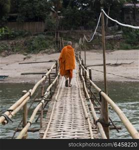 Monk walking on bamboo bridge over Nam Khan river, Luang Prabang, Laos