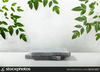 Monochrome gray template for mockup, banner. Flat granite pedestal and green leaves on light gray background. Stone stand for natural design concept. Horizontal image, center composition, hard light, front view