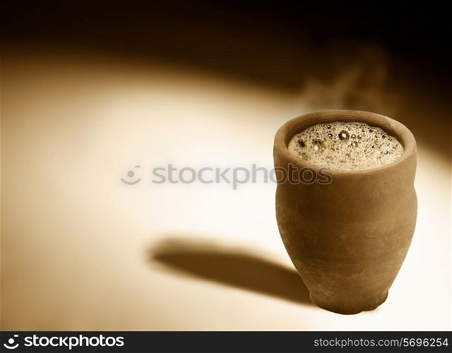 Monochrome image of hot steaming chai in traditional cup made of mud