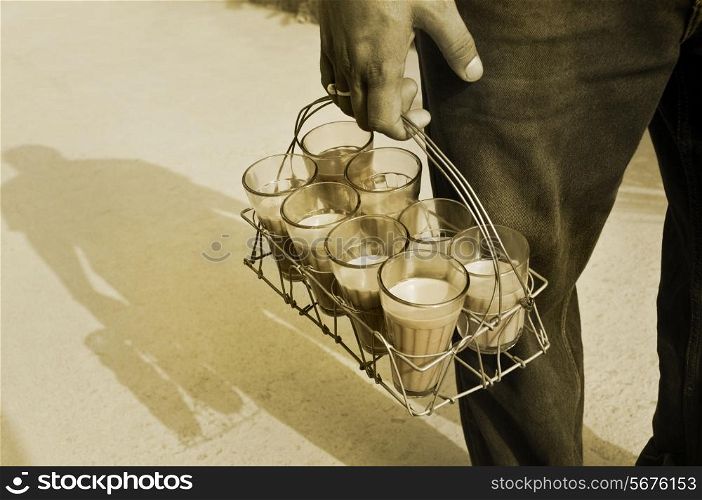 Monochrome image of Indian street holding glasses of chai in tray