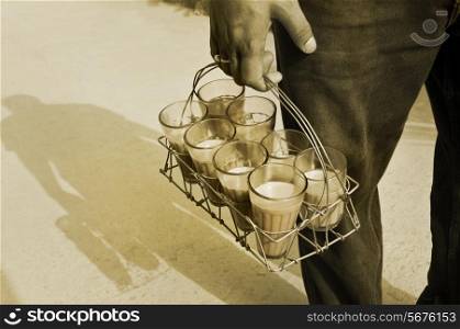 Monochrome image of Indian street holding glasses of chai in tray