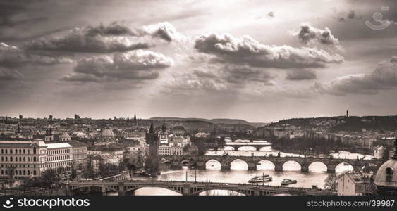 Monochrome image with the old center of Prague, the capital of Czech Republic, with its antique bridges and historical buildings, under a dramatic sky.