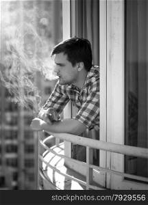 Monochrome portrait of depressed man smoking cigarette