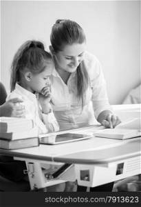 Monochrome portrait of happy mother and daughter doing homework
