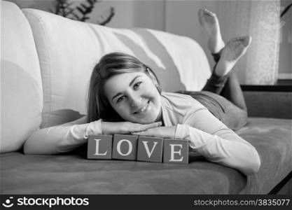 Monochrome portrait of happy smiling woman lying on couch with word