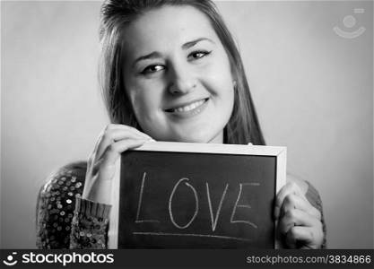 Monochrome portrait of smiling woman posing with blackboard with word