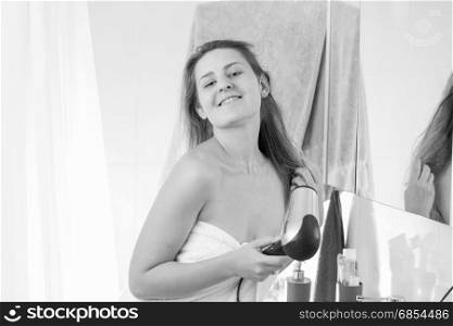 Monochrome portrait of young woman drying hair after having shower