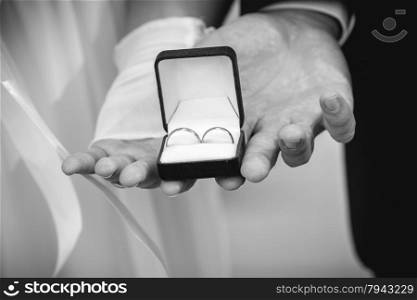 Monochrome shot of bride and groom holding box with wedding rings