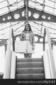 Monochrome shot of woman descend the escalator at railway station