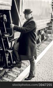 Monochrome toned photo of man in bowler hat walking inside of retro train