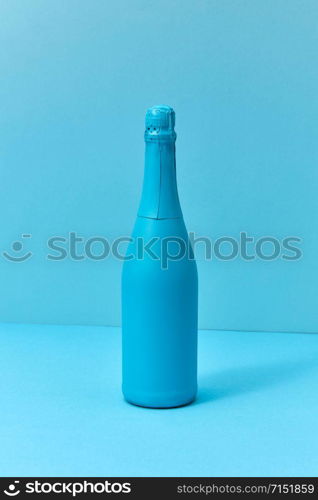 Monotone blue composition painted champagne mock up bottle with soft shadows with copy space. Minimal concept.. Holiday champagne mock up bottle painted blue with soft shadows.