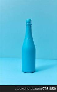 Monotone blue composition painted champagne mock up bottle with soft shadows with copy space. Minimal concept.. Holiday champagne mock up bottle painted blue with soft shadows.