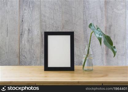 monstera leaf glass bottle frame wooden table. High resolution photo. monstera leaf glass bottle frame wooden table. High quality photo