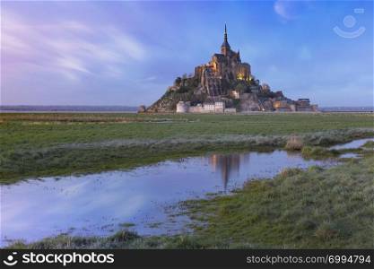 Mont Saint Michel at sunset with reflection in the canal on the water meadows, Normandy, France. Mont Saint Michel at sunset, Normandy, France