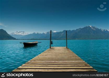 Montreux, VD / Switzerland - 31 May 2019: mountain and lake landscape with a vintage rescue rowboat and a wooden pier