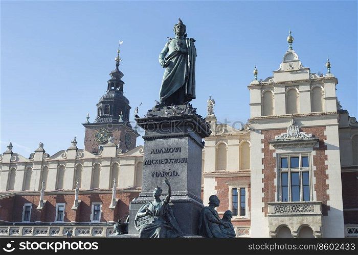 Monument of Adam Mickiewicz in Krakow by clock tower, Poland