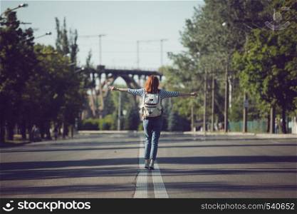 mood. girl with a backpack is walking on an empty road