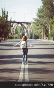 mood. girl with a backpack is walking on an empty road
