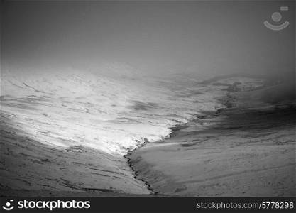 Moody dramatic low cloud Winter landscape in mountains in black and white