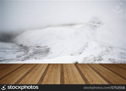 Moody dramatic low cloud Winter landscape in mountains with snow on ground with wooden planks floor