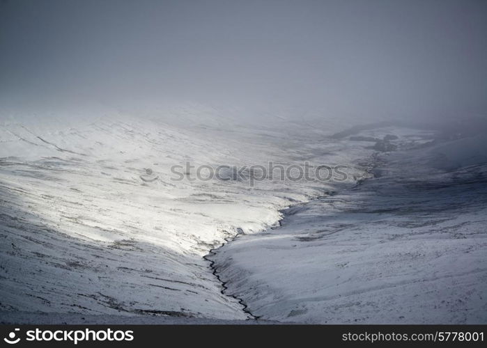 Moody dramatic low cloud Winter landscape in mountains with snow on ground