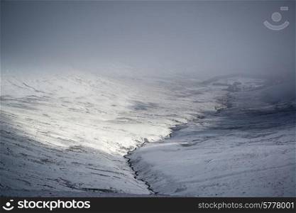 Moody dramatic low cloud Winter landscape in mountains with snow on ground
