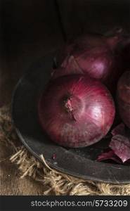 Moody natural light vintage style image of fresh red onions. food, fresh, raw, fruit, vegetables, wood, wooden, background, grunge, retro, vintage, moody, dark,