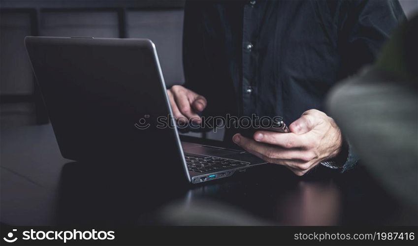 Moody office with a businessman with samrtphone and notebook
