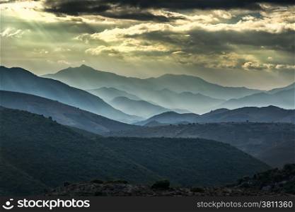 Moody skies and sunshine over receding mountains in the Balagne region of Corsica