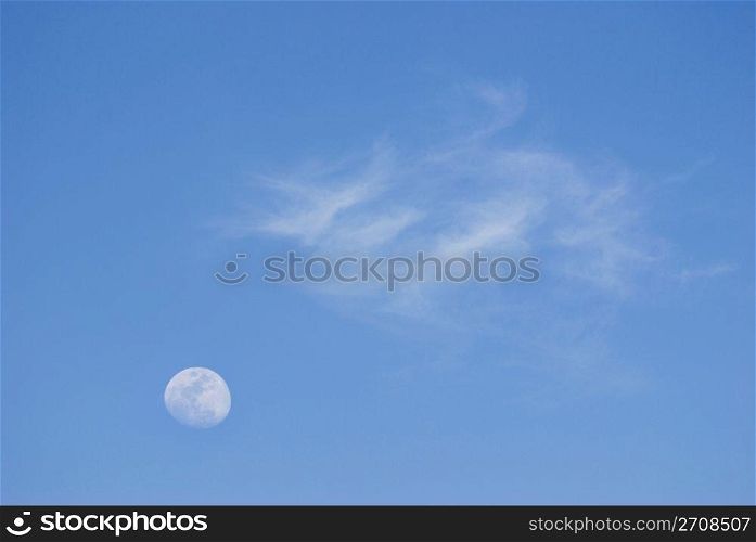 Moon and soft clouds in evening sky, peaceful day.