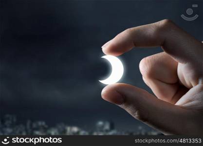Moon between fingers. Close view of male hand taking moon symbol with fingers