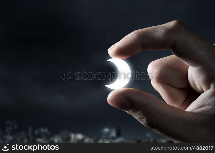 Moon between fingers. Close view of male hand taking moon symbol with fingers
