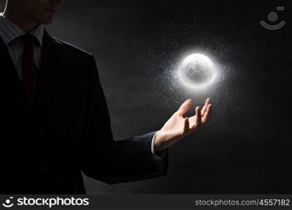 Moon glowing in darkness. Close up of businessman holding moon planet in palm