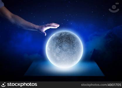 Moon in hand. Close up of human hand touching moon planet