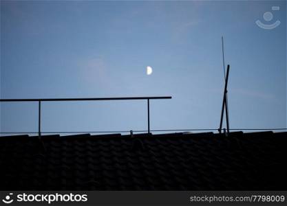 moon in the night sky above the roof