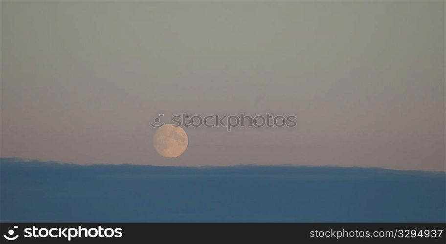 Moon rising over the cloudy horizon