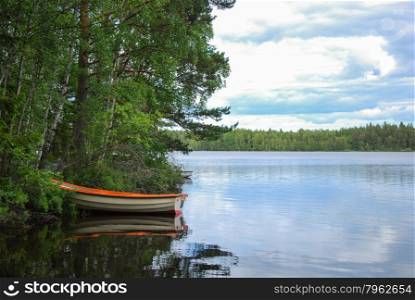Moored rowing boat at a peaceful bay of a lake in the swedish province Smaland