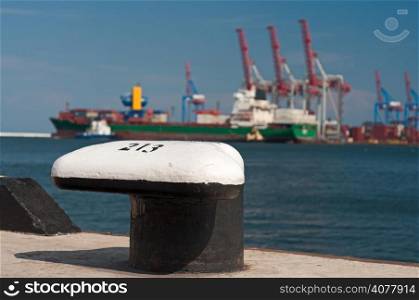 Mooring Post with ship and port cranes on the blurred background