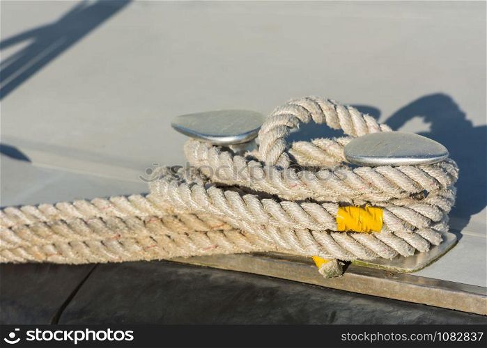 Mooring rope with a knotted end tied around a cleat on a wooden pier