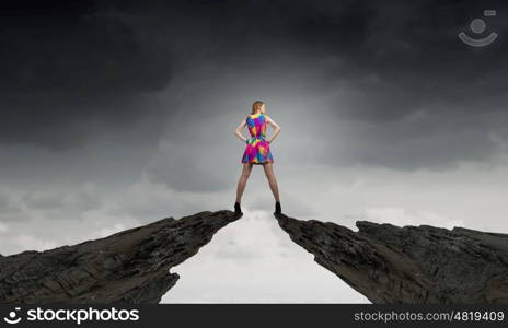 More colors. Young girl in multicolored bright dress on rock top