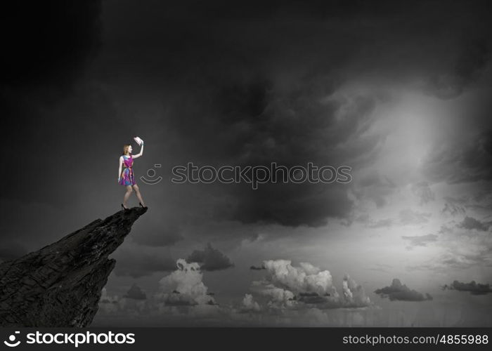 More colors. Young girl in multicolored bright dress on rock top